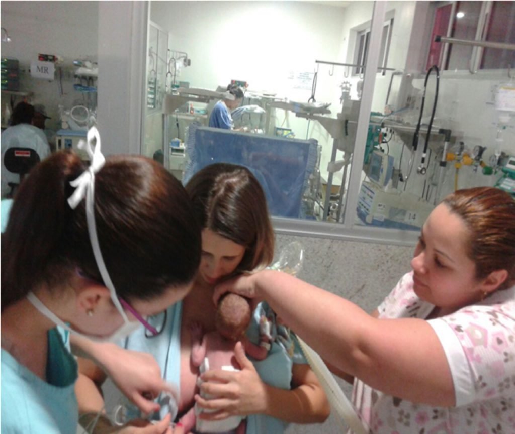 Equipe multidisciplinar do projeto auxiliando uma paciente do grupo intervenção a amamentar seu prematuro